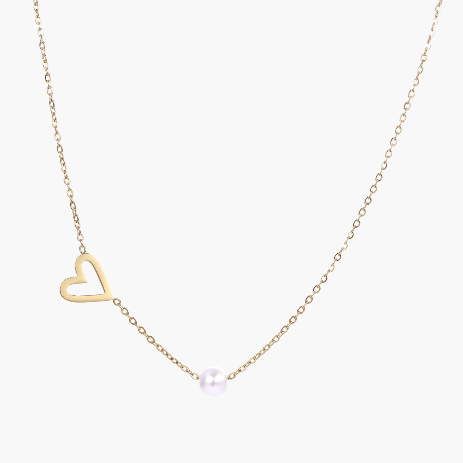 Delicate gold necklace with open heart charm and white pearl bead on fine chain against cream background