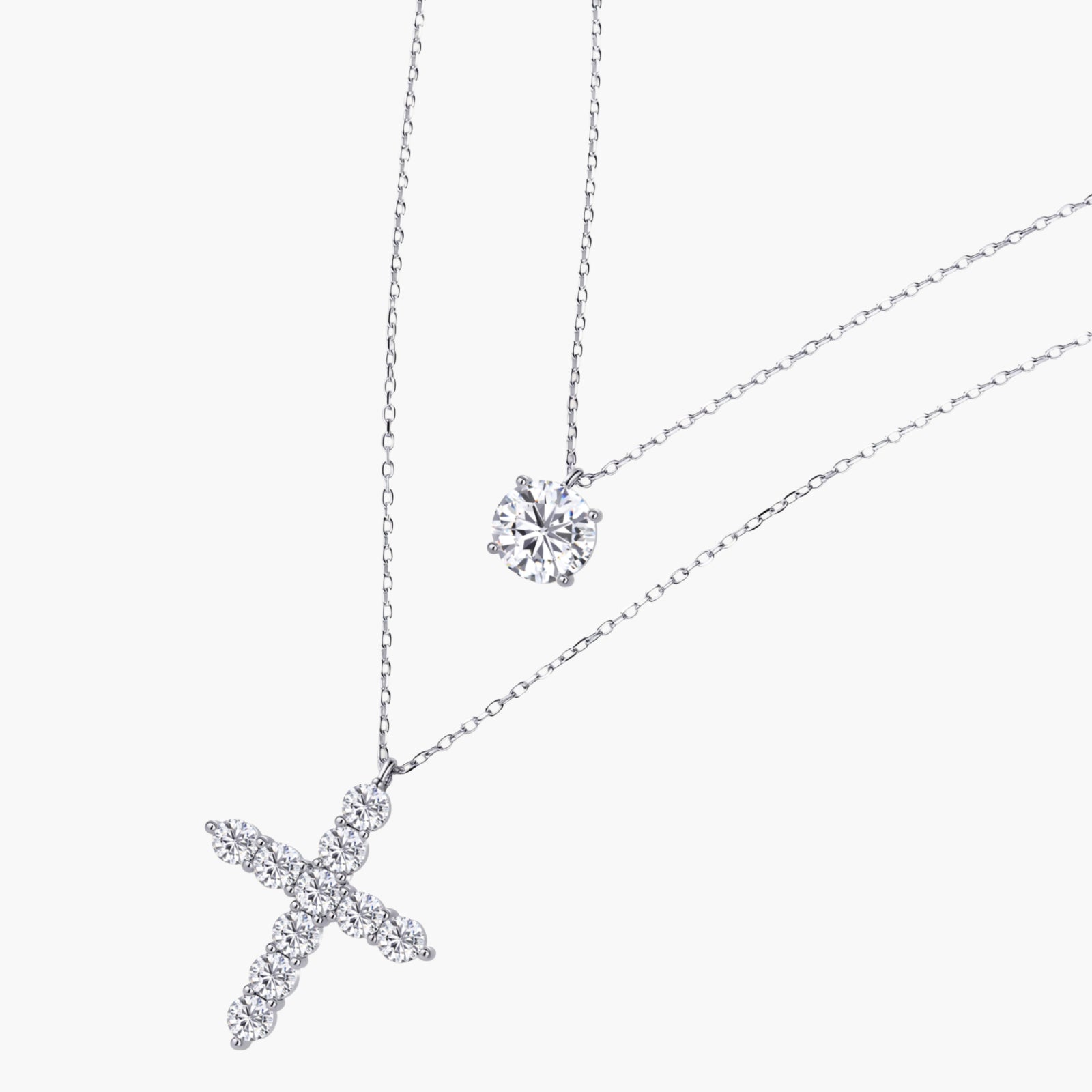 Two delicate sterling silver necklaces with moissanite stones - one solitaire pendant and one cross pendant on white background.