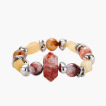 Stretch bracelet with amber citrine beads, red crystal stones and brass accents featuring a hexagonal centerpiece on white background.